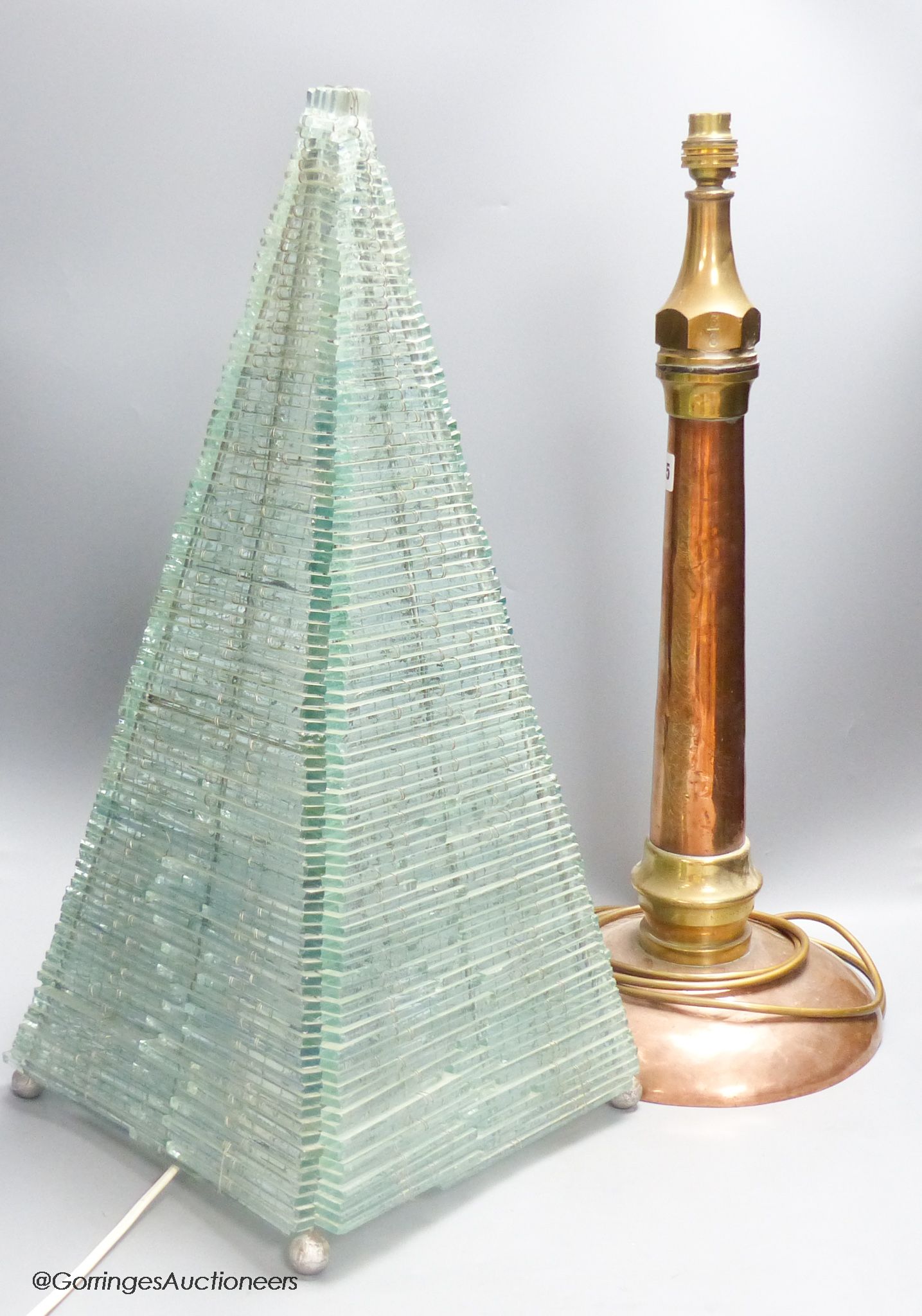 A large copper and brass hose lamp and a modern glass pyramid lamp, tallest 56cm